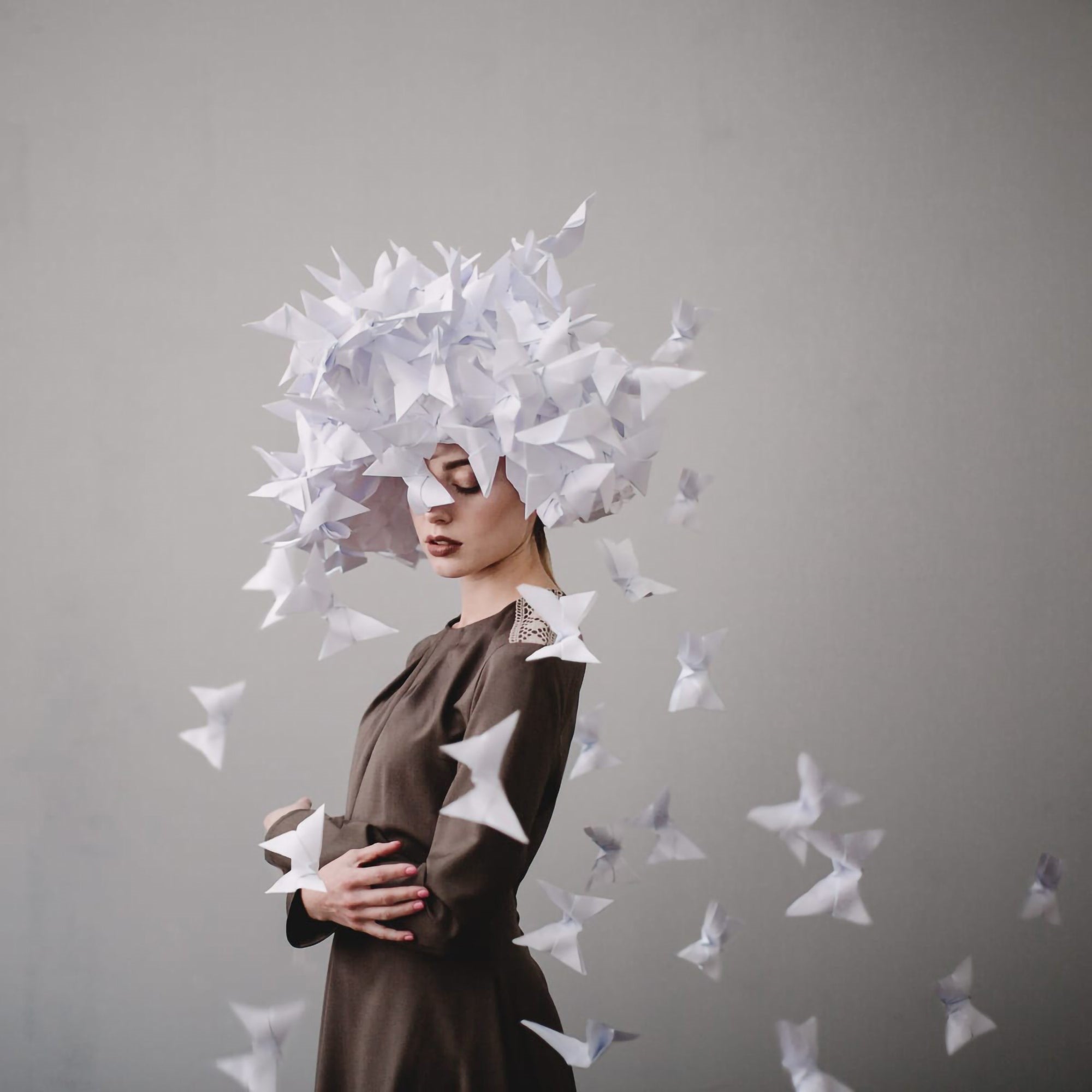 Paper butterflies ascend around a quiet figure in soft, surreal tones.