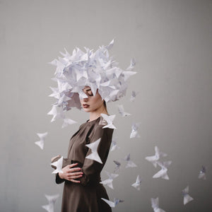 Paper butterflies ascend around a quiet figure in soft, surreal tones.